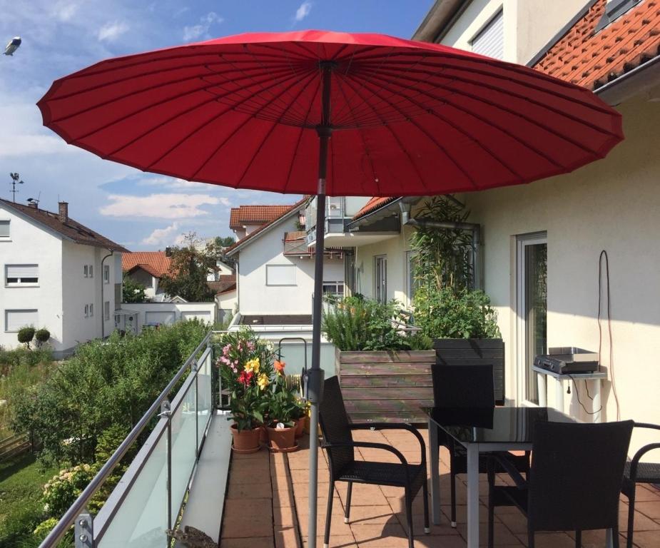 a red umbrella on a balcony with a table and chairs at HappyTime in Eriskirch