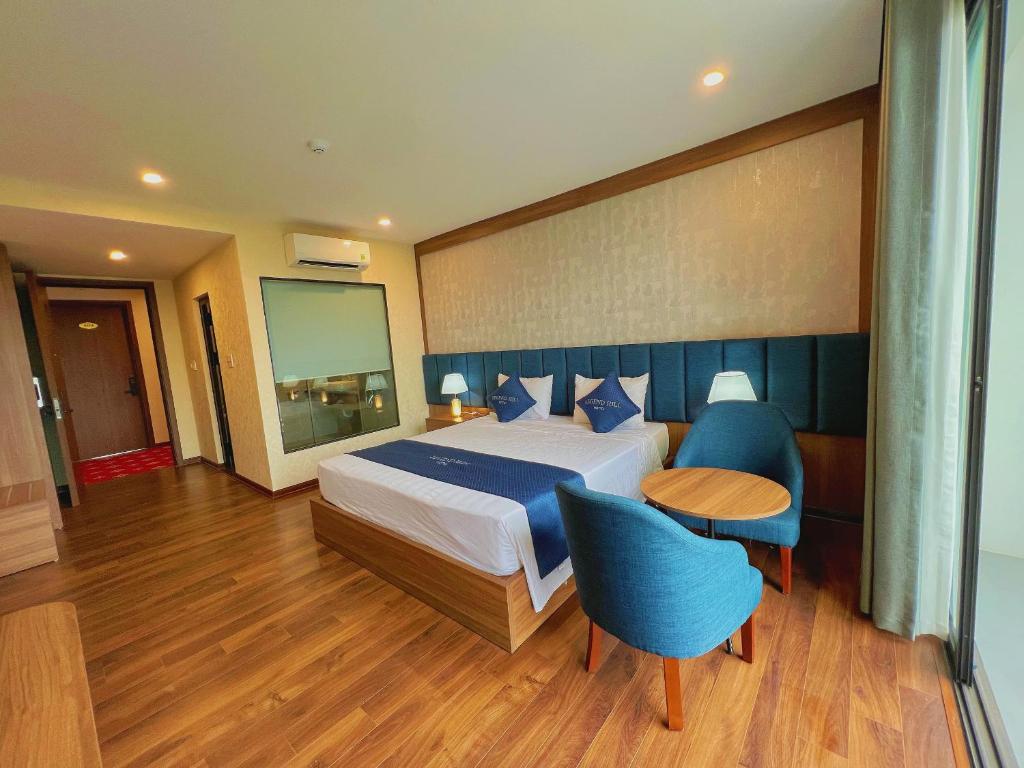 a bedroom with a bed and a table and blue chairs at Thái Nguyên Legend Hill 