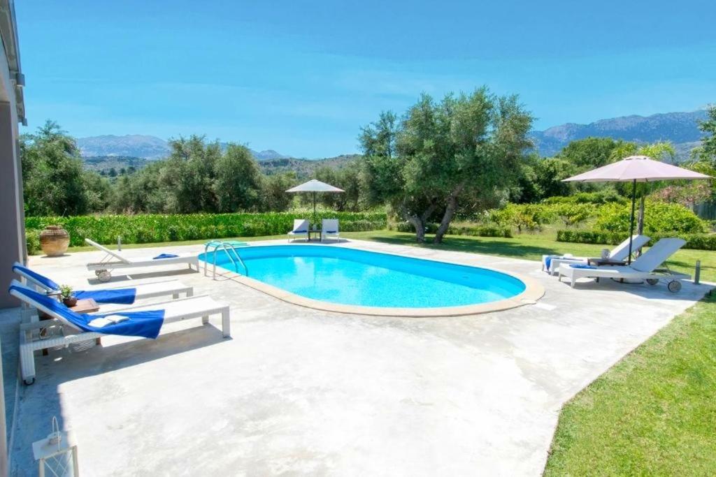 una piscina en un patio con sillas y sombrillas en Villa Felenia - Private Pool, en Vryses