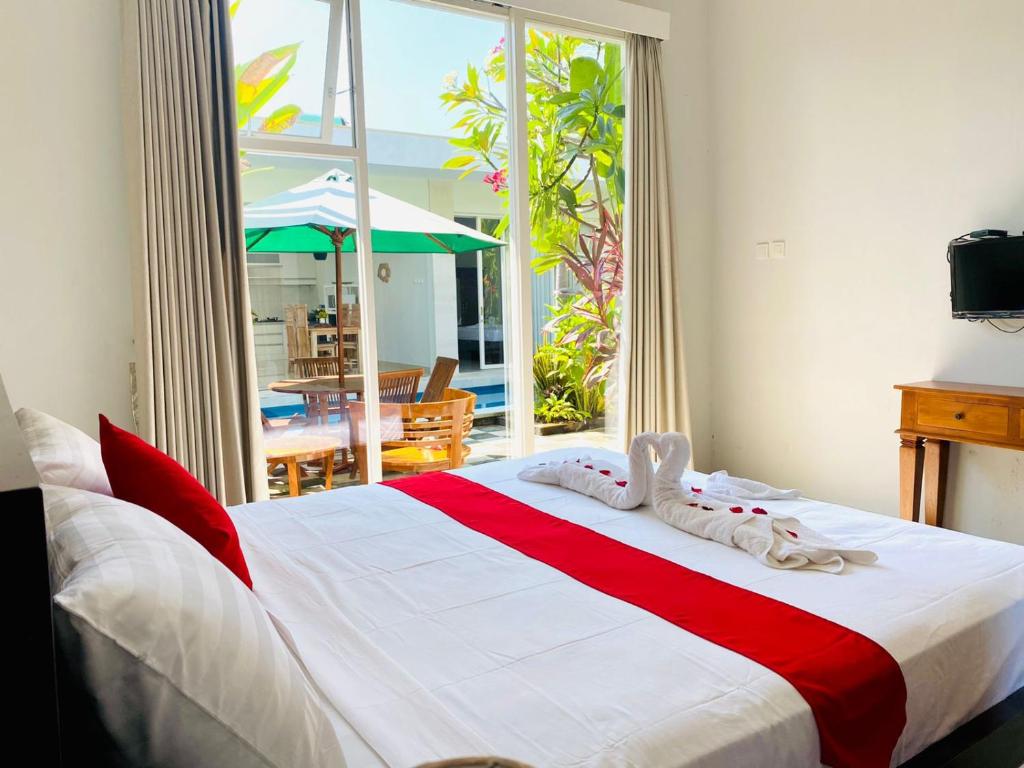 a bedroom with a large bed with red and white sheets at Villa WENHOMANN in Lovina