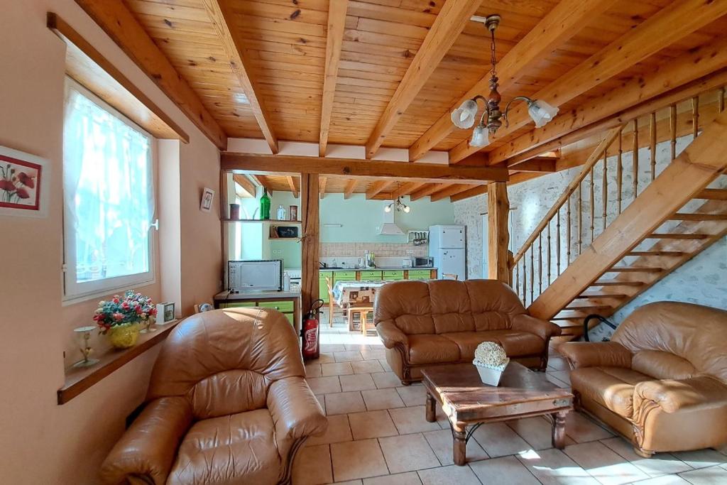 a living room with leather furniture and a wooden ceiling at Les Glycines in Saint-Pierre-de-Buzet