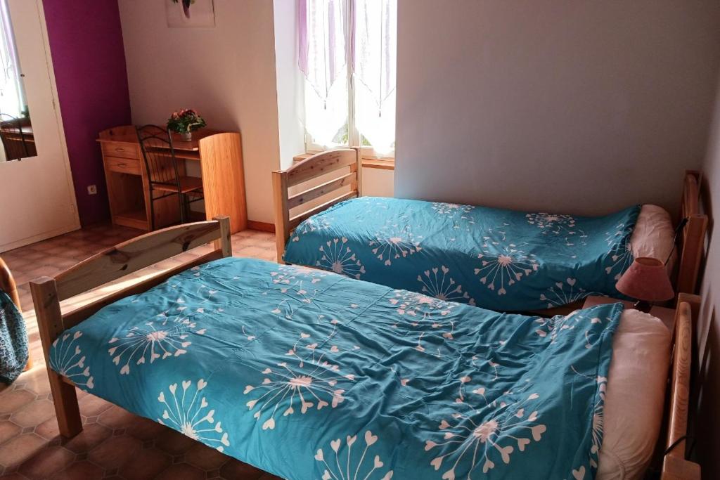 a bedroom with two beds with blue sheets at Les Glycines in Saint-Pierre-de-Buzet