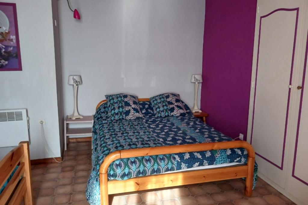 a small bedroom with a bed with a blue comforter at Les Glycines in Saint-Pierre-de-Buzet