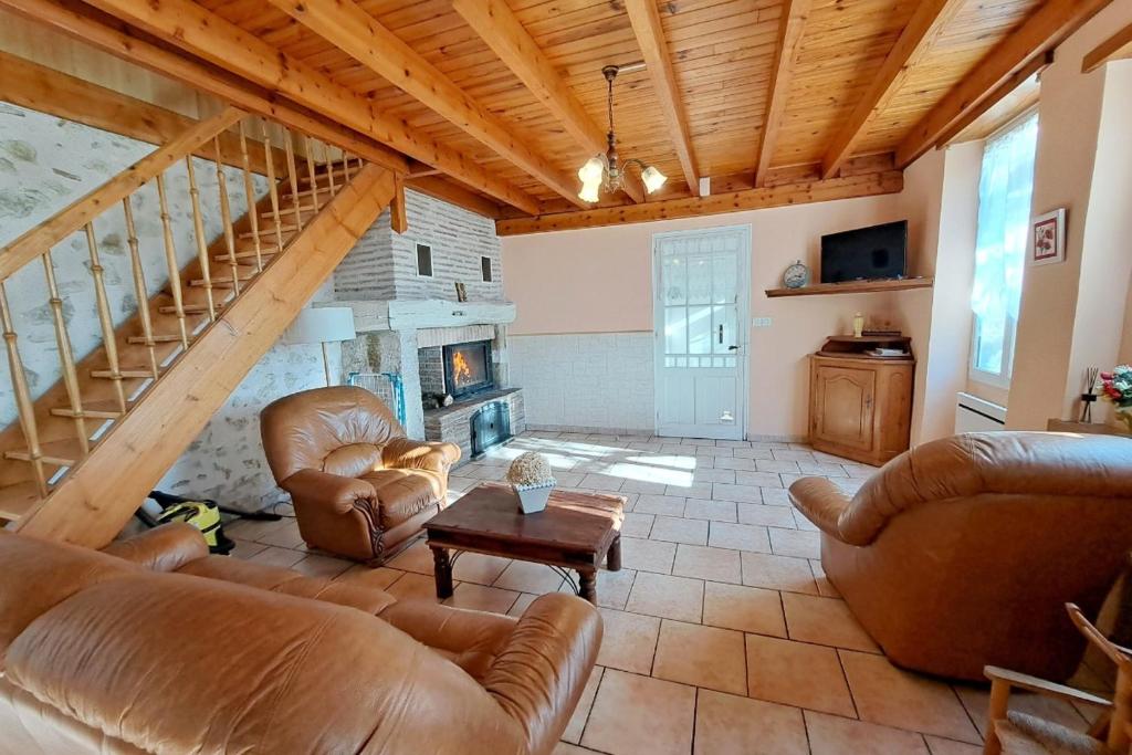 a living room with leather furniture and a stone fireplace at Les Glycines in Saint-Pierre-de-Buzet