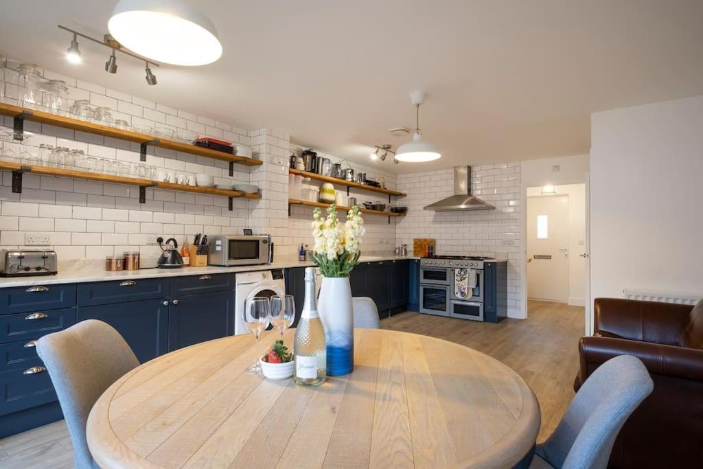 a kitchen with a wooden table and blue cabinets at Comfortable townhouse in Tetbury, parking & garden in Tetbury