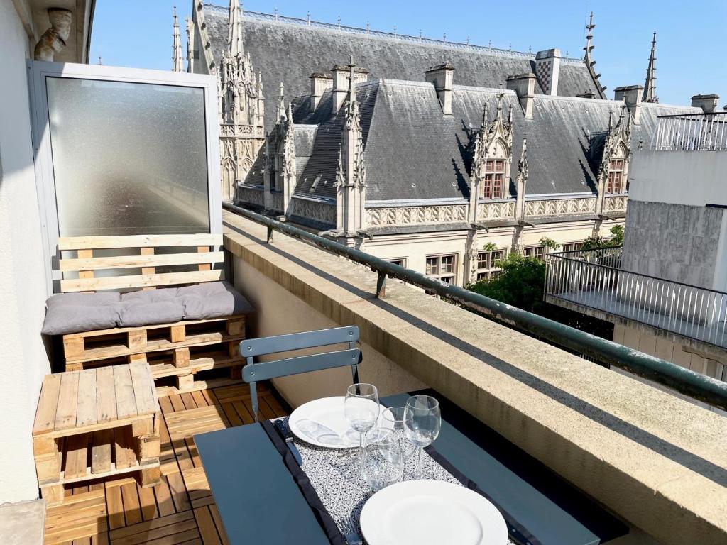 stół i krzesła na balkonie z widokiem na budynek w obiekcie Appartement A Deux Pas situé en Hyper Centre Ville w Rouen