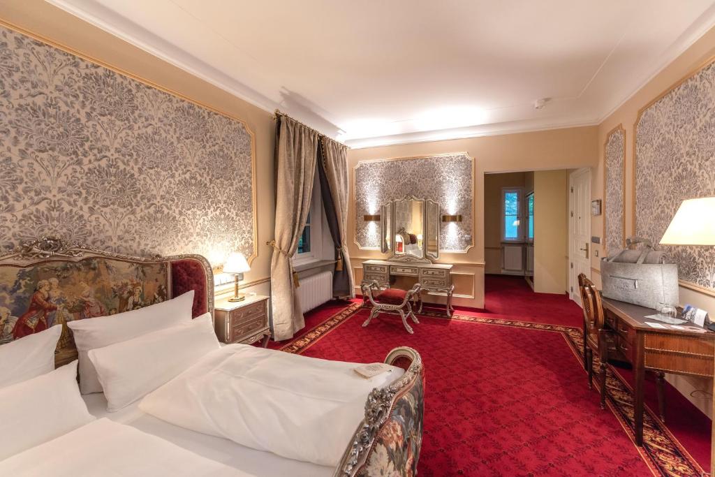 ツヴィーゼルにあるRobenstein Hotel & SPA - Villaのベッドとデスクが備わるホテルルームです。