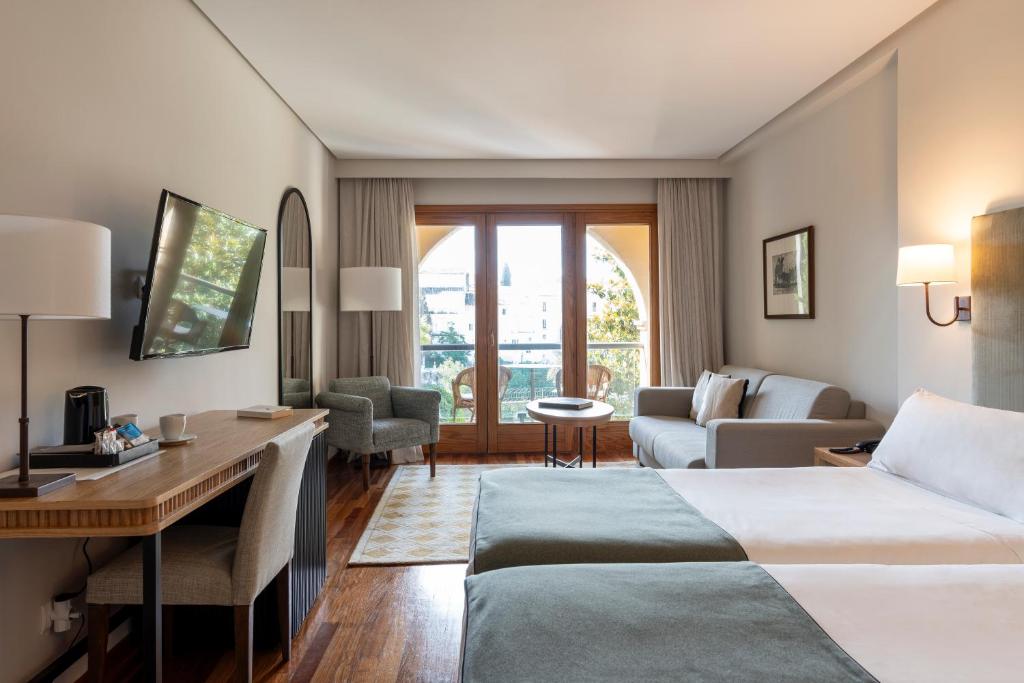 ロンダにあるパラドール デ ロンダのベッド2台とデスクが備わるホテルルームです。