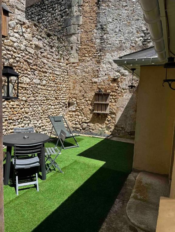 a patio with a table and chairs and a stone wall at La Petite Rochambelle (hyper centre-ville) in Vendôme