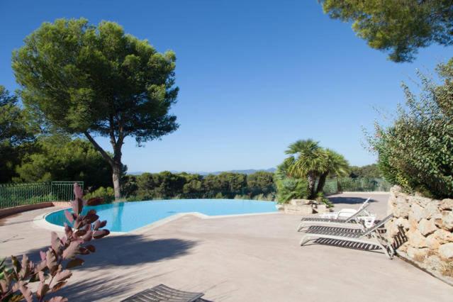 - une piscine avec 2 chaises longues et un arbre dans l'établissement Fantastisk feriebolig med basseng og kort vei til havet, à Saint-Raphaël