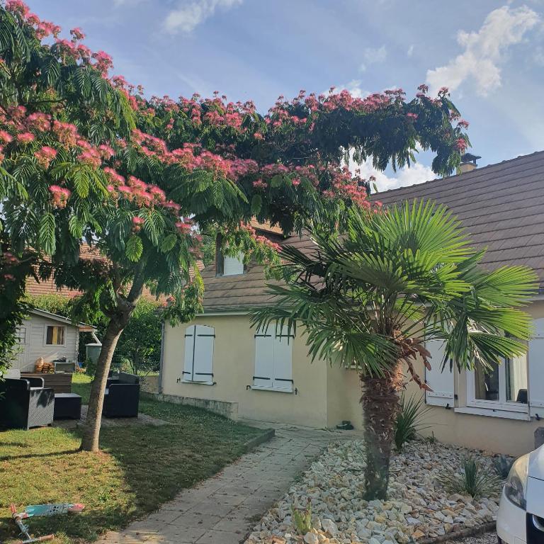 un arbre aux fleurs roses devant une maison dans l'établissement Maison familliale à la campagne à 15 min du mans, à Roézé-sur-Sarthe