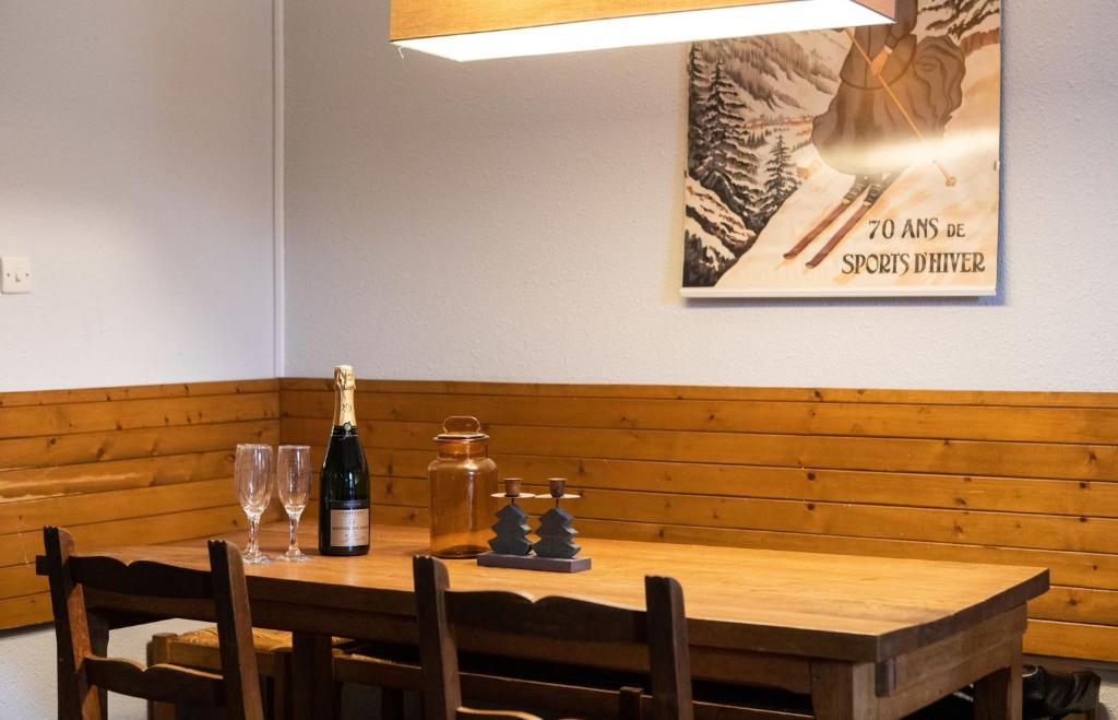 - une table en bois avec une bouteille de vin et 2 verres dans l'établissement IMMODREAMS - Le Mazot, à Morzine