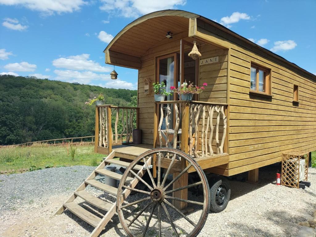a wooden tiny house with a large wheel at La roulotte de Jane in Margon