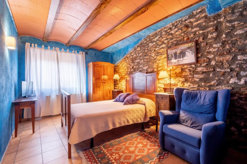 een slaapkamer met een bed en een blauwe stoel bij Rural Jordà in Rodonyà