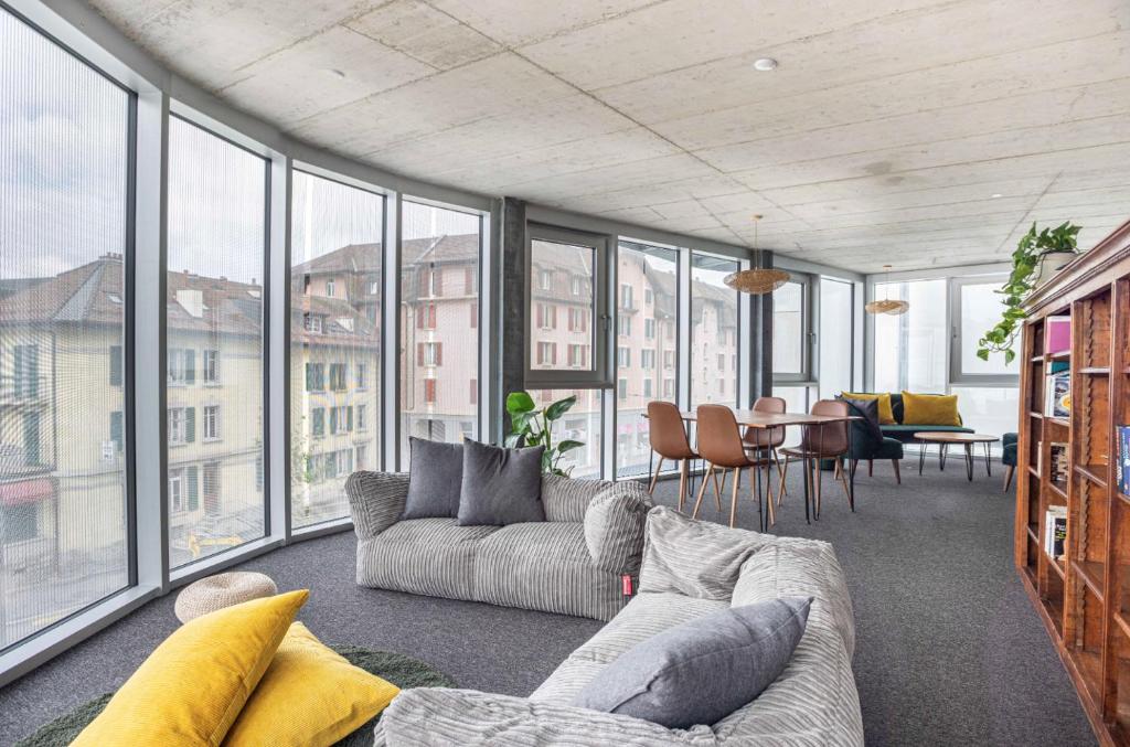 a living room with a couch and a table with chairs at Lumen by coliving in Renens