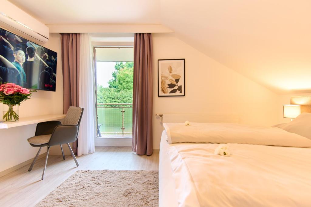 1 dormitorio con 2 camas, escritorio y ventana en Pension - Ferienwohnungen Zollner en Villach