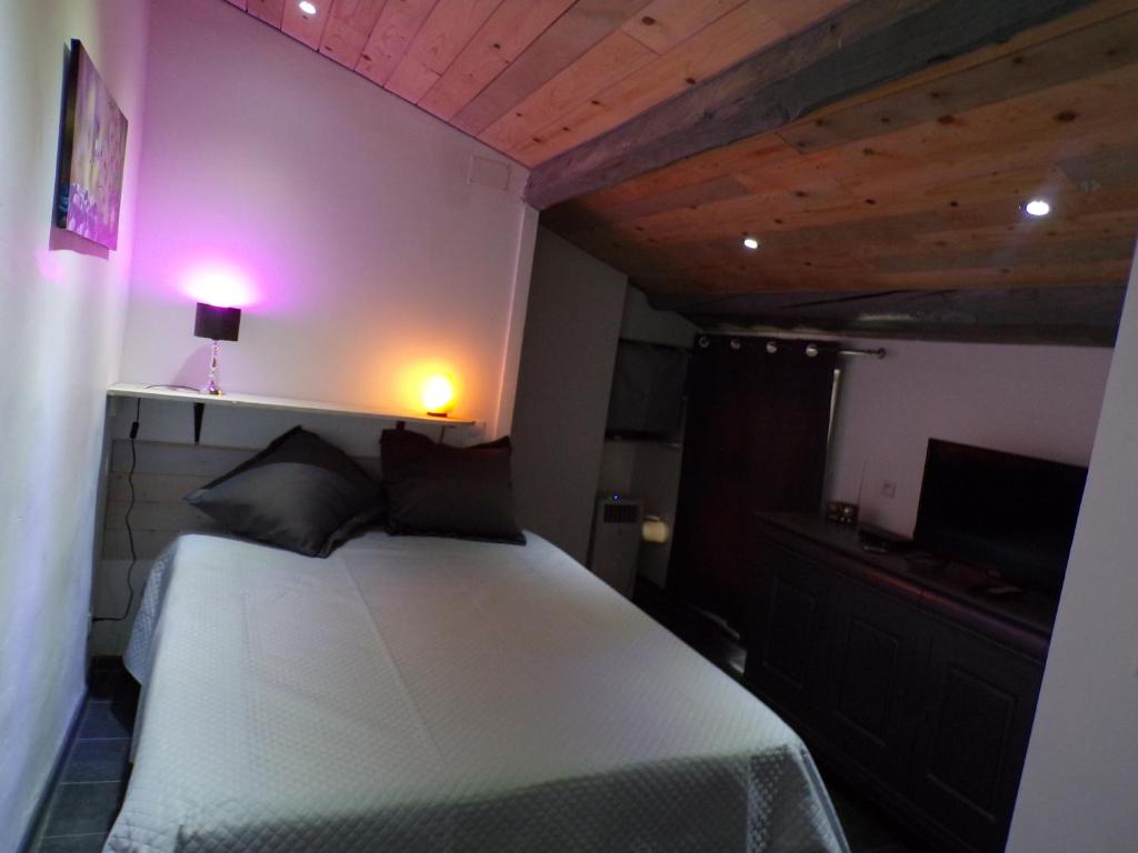 a bedroom with a white bed with two black pillows at INSOLITE STUDIO -La Tour des Templiers- in Montfrin