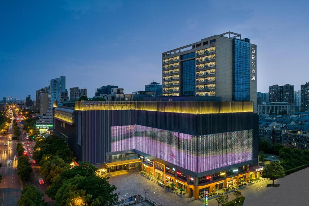 杭州市にあるAtour X Hotel Hangzhou Wenyi Roadの街のライトアップファサード付きの大きな建物