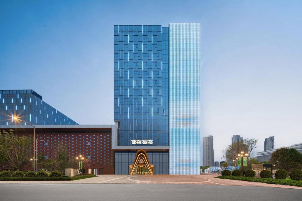 a tall glass building in front of a city at Atour Hotel Nantong Longxin Plaza in Nantong