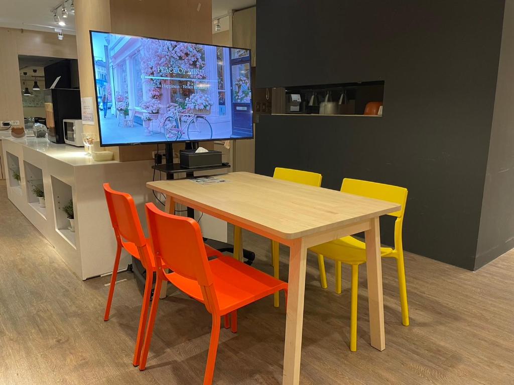 a dining room table with colorful chairs and a television at Yomi Hotel - ShuangLian MRT in Taipei