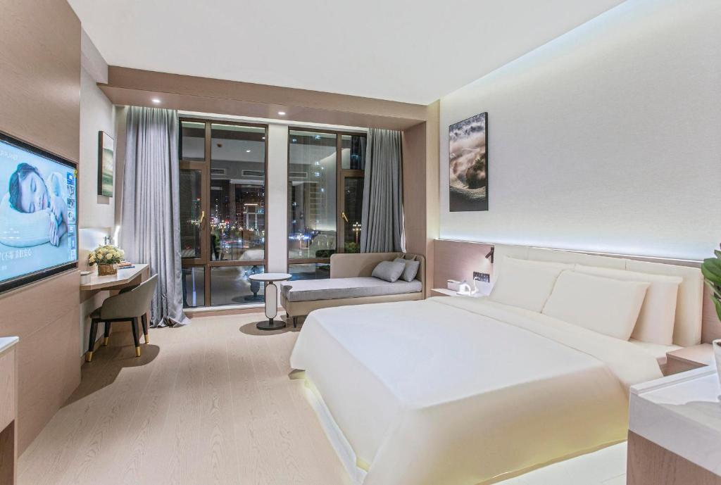 1 dormitorio con 1 cama blanca grande y TV en Atour X Hotel Chuxiong Yihai Park, en Chuxiong