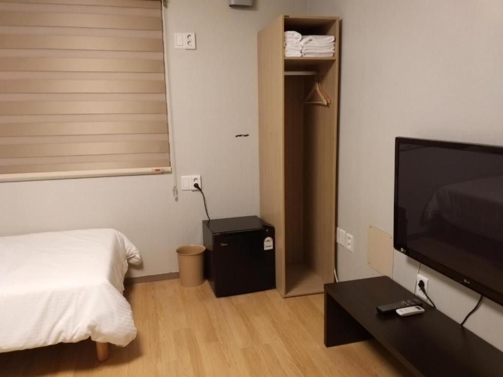 1 dormitorio con 1 cama y TV de pantalla plana en Uniqstay, en Busan