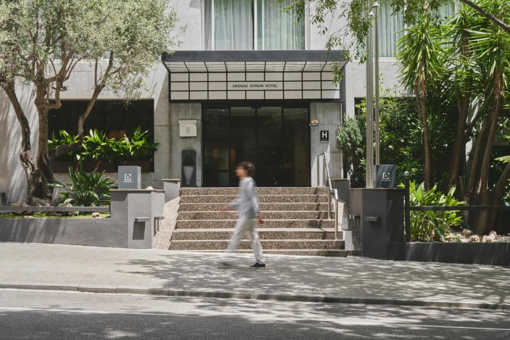 uma mulher andando pela rua em frente a um prédio em Arenas Atiram Hotels em Barcelona