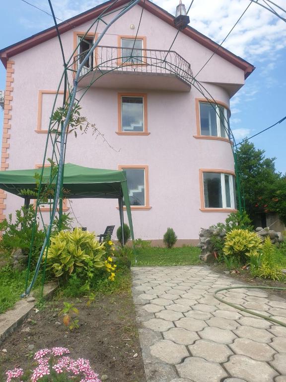 ein großes rosafarbenes Haus mit grünem Dach in der Unterkunft Гостевой дом in Ekadiya