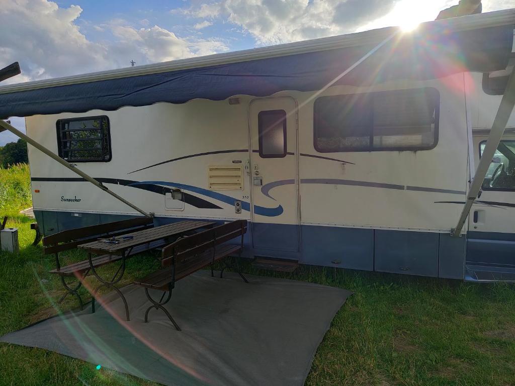 una caravana blanca y azul estacionada en un campo en KAMPER NAD BRZEGIEM JEZIORA NIEGOCIN, en Giżycko