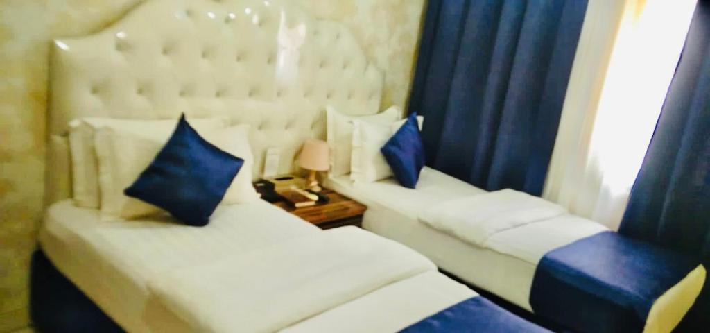 two white beds with blue pillows in a room at Golden Star Hotel in Dubai