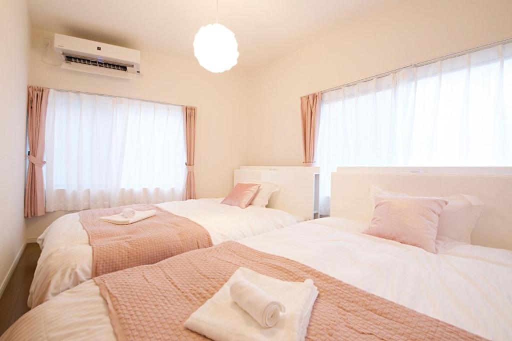 a bedroom with two beds and a window at Primehome Ninomiya in Fukiaichō