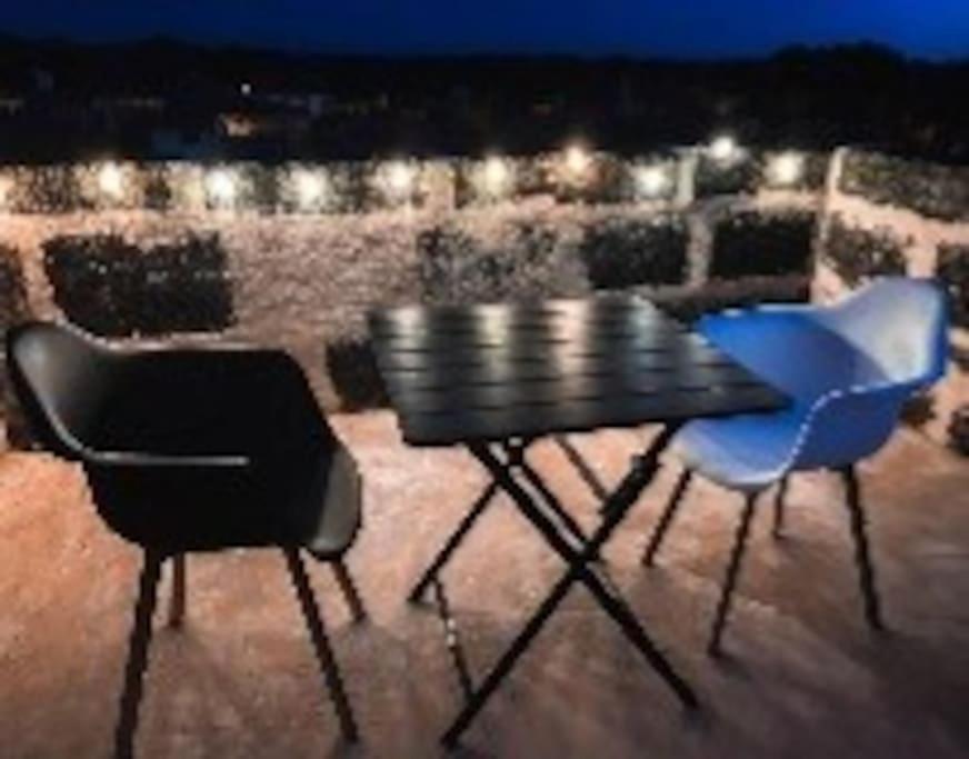 two chairs and a table on a balcony at night at Gite de la tour, proche Nîmes ,Avignon in Montfrin