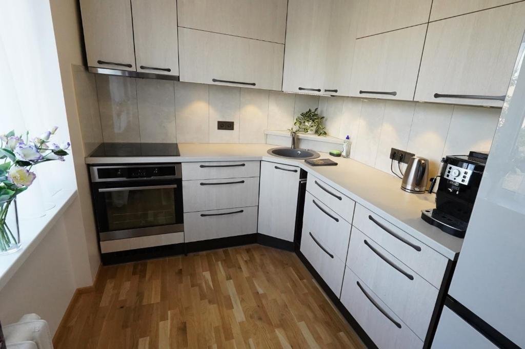 a kitchen with white cabinets and a wooden floor at Promenaadi Apartment in Võru