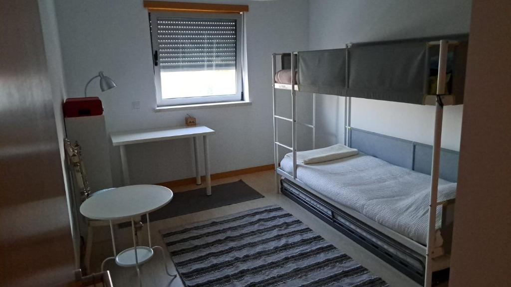 sypialnia z łóżkiem piętrowym, stołem i oknem w obiekcie Perola da Figueira da Foz w mieście Figueira da Foz