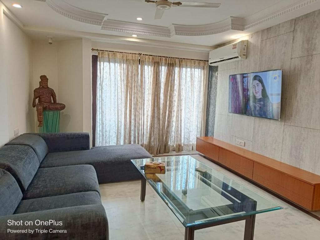 een woonkamer met een bank en een glazen tafel bij Dynamic Room(R3) Embellished with Excellence-Heart of City in New Delhi