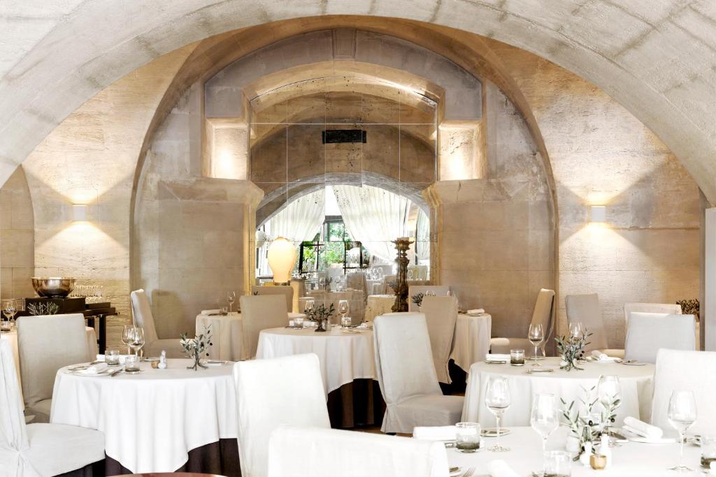 a dining room with white tables and white chairs at Baumanière - Les Baux de Provence in Les Baux-de-Provence