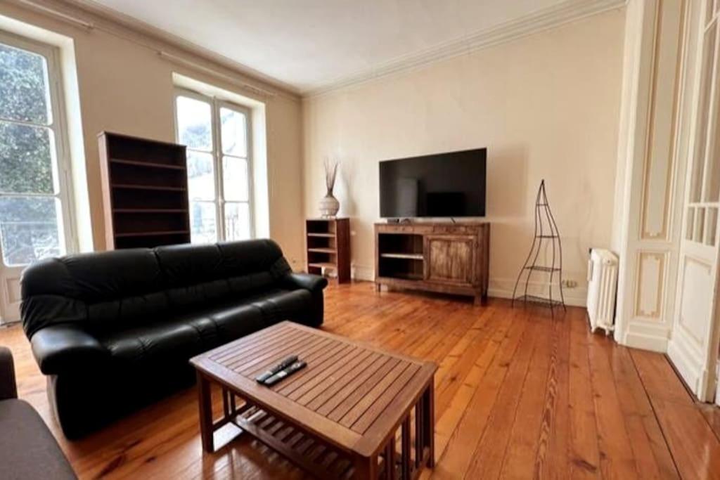 uma sala de estar com um sofá de couro preto e uma televisão em Appartement en coeur de village em Bourg-sur-Gironde