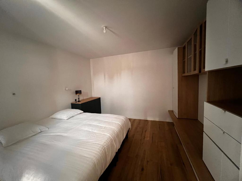 um quarto com uma grande cama branca e pisos em madeira em House Prestige em Juvignac