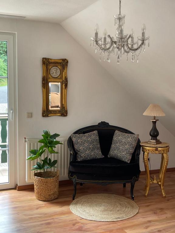 sala de estar con silla y lámpara de araña en Pension Hühnermühle en Volkerode