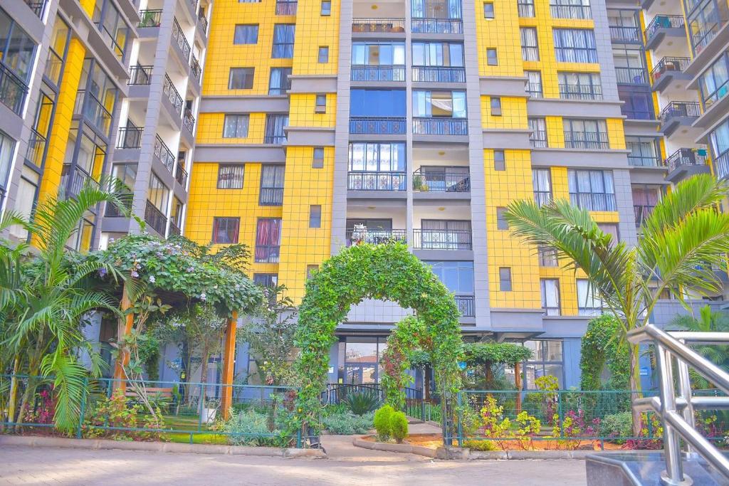 a tall yellow building with trees in front of it at Chic 2-Bedroom Haven in Kilimani in Nairobi