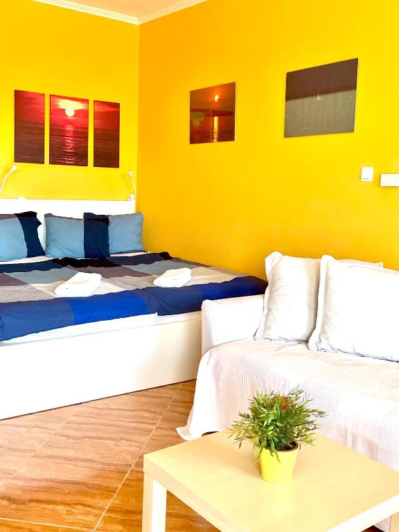 Pokój z 2 łóżkami, stołem i żółtą ścianą w obiekcie Balaton BeachSide Apartman Siófok N3 w Siófoku