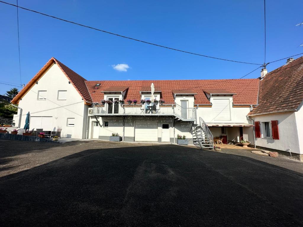 a large white house with a balcony on a street at Au parfum des roses in Gunstett