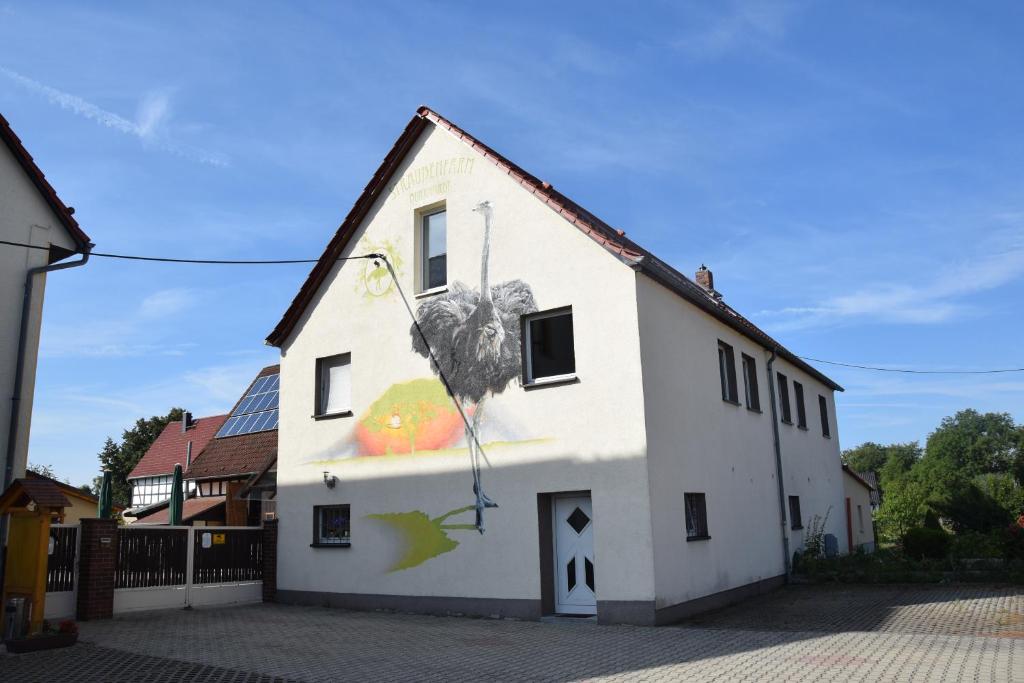 a white building with a painting on the side of it at Ferienwohnungen Straußenfarm Burkhardt in Schmölln