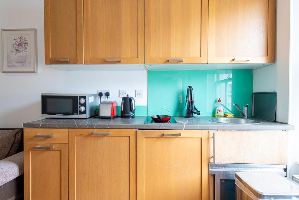 a kitchen with wooden cabinets and a microwave at London Central Studio in London