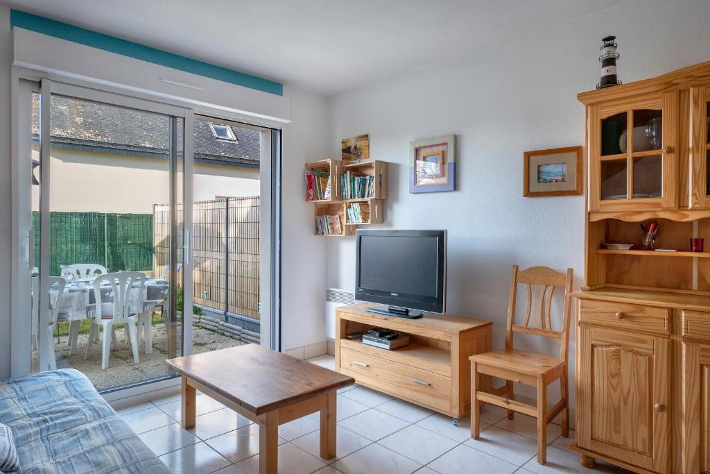 uma sala de estar com uma televisão, uma cadeira e uma mesa em Maison confortable et familiale pour 6 personnes em Sarzeau