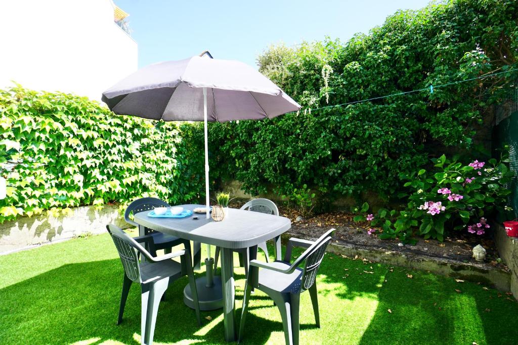 a table and chairs with an umbrella on the grass at Cabine de plage n°2 *50m de la plage* in Ploemeur