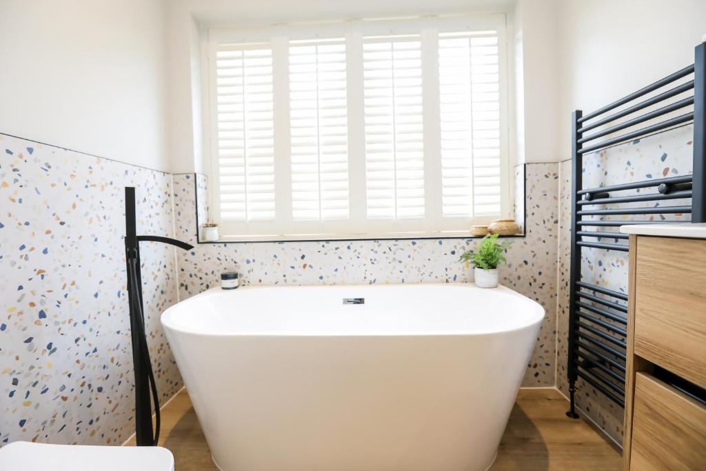 baño con bañera blanca y ventana en Beautiful boutique feel centrally located en Hereford