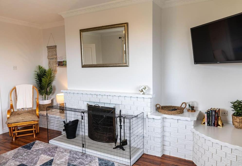 a living room with a white brick fireplace with a mirror at Ligford Cottage 