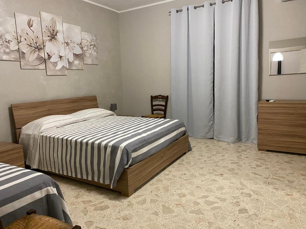 a bedroom with a bed and a window with curtains at Nonna Maria Rosa in Senise