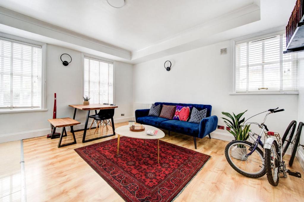 GuestReady - Charming stay in Limehouse في لندن: غرفة معيشة مع أريكة زرقاء وطاولة